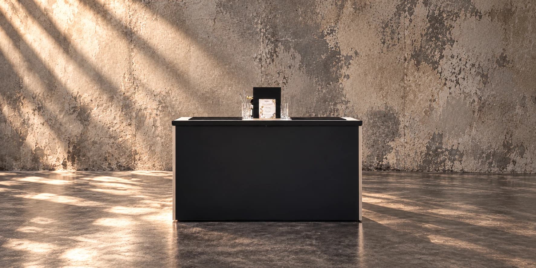 Le bar lumineux noir mat d’Azur Drinks, installé dans un volume de béton