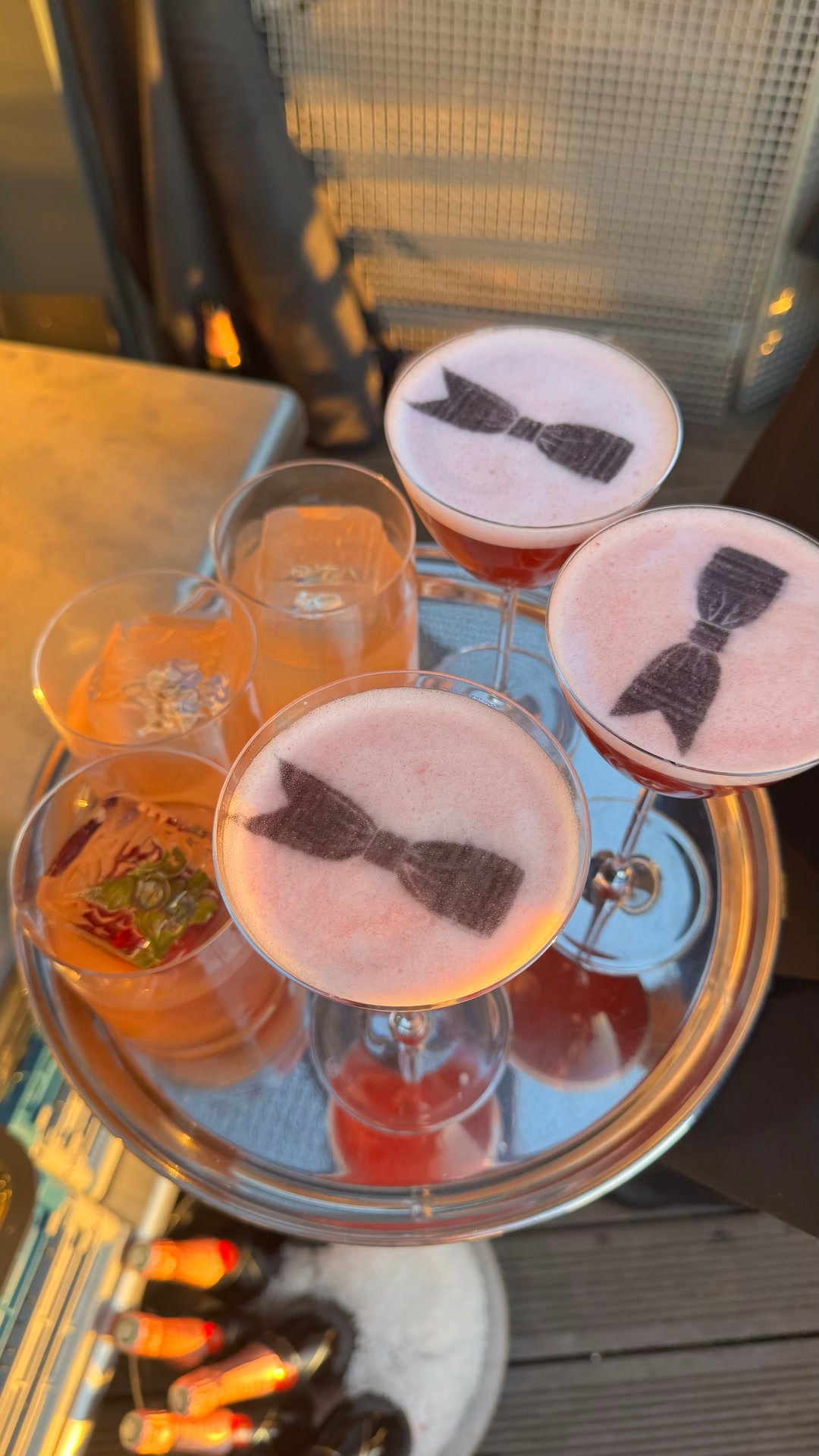 Trois coupes de cocktail rose, chacune portant un nœud papillon imprimé sur la mousse