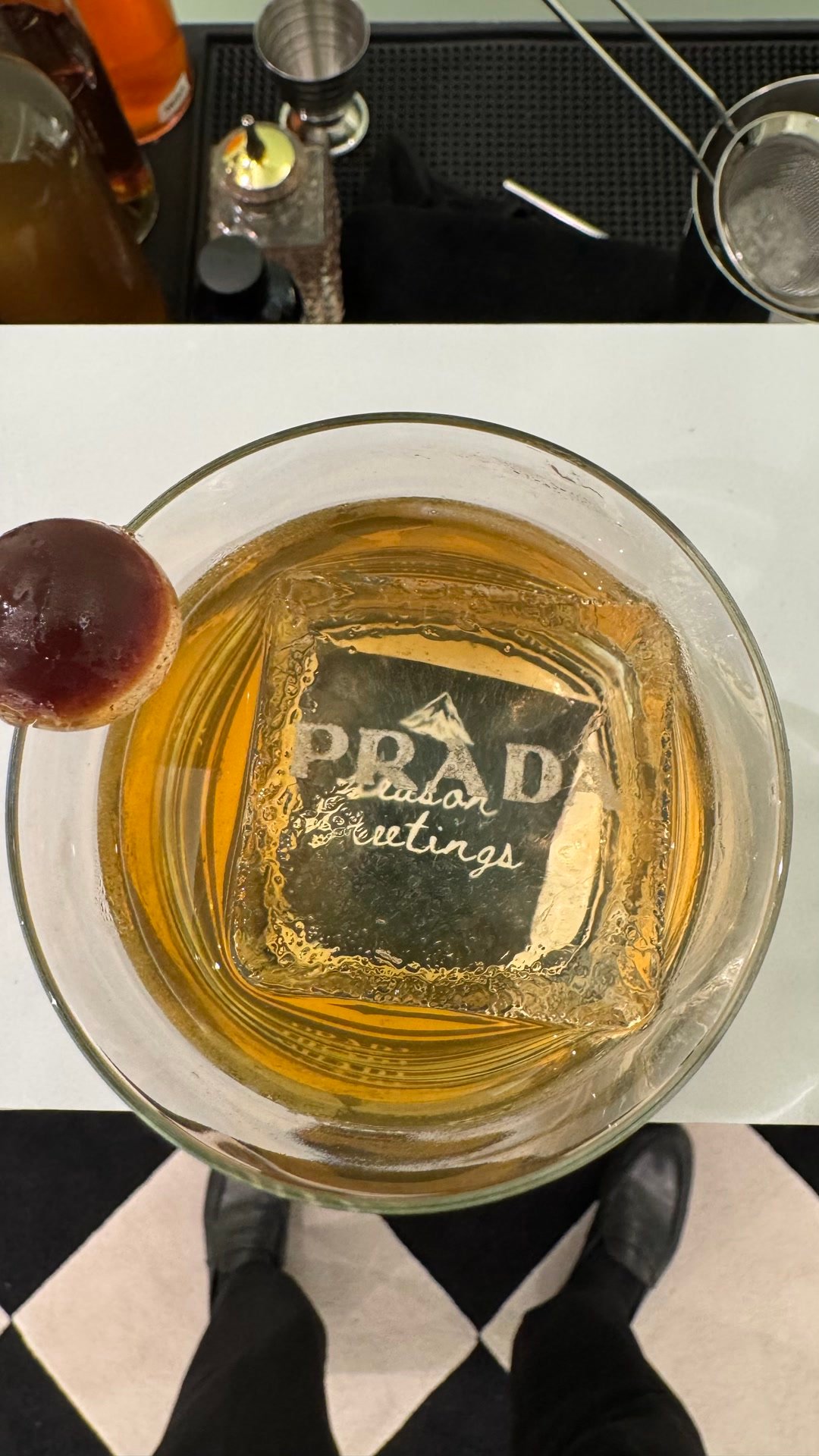 Cocktail ambré vu du dessus, avec un glaçon carré gravé d'un logo